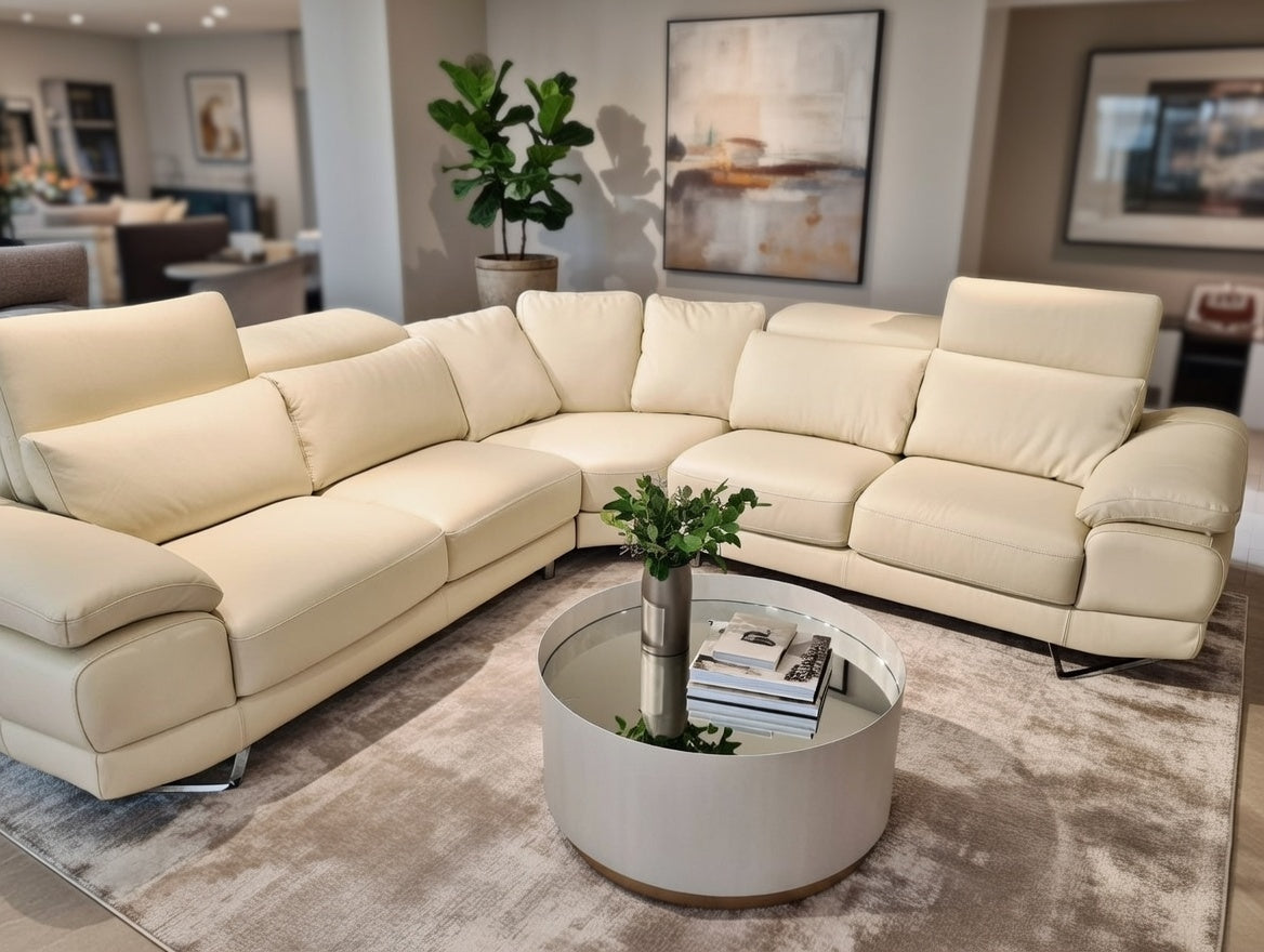 Large cream leather corner sofa with adjustable headrests and chrome feet.