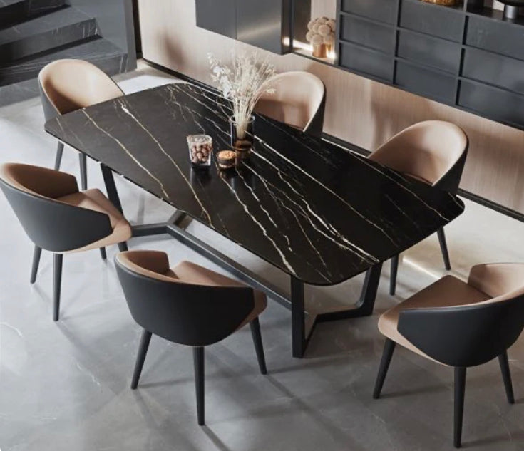 curved dining chair upholstered in tan and black leather with dark wooden legs. Black marble top dining table.