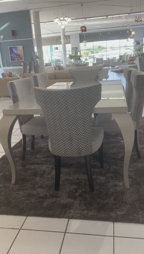 The elgant and opulent UNIQUE dining table is a 6-8 seater table with vintage curved legs, gloss grey wood and a tempered glass top.