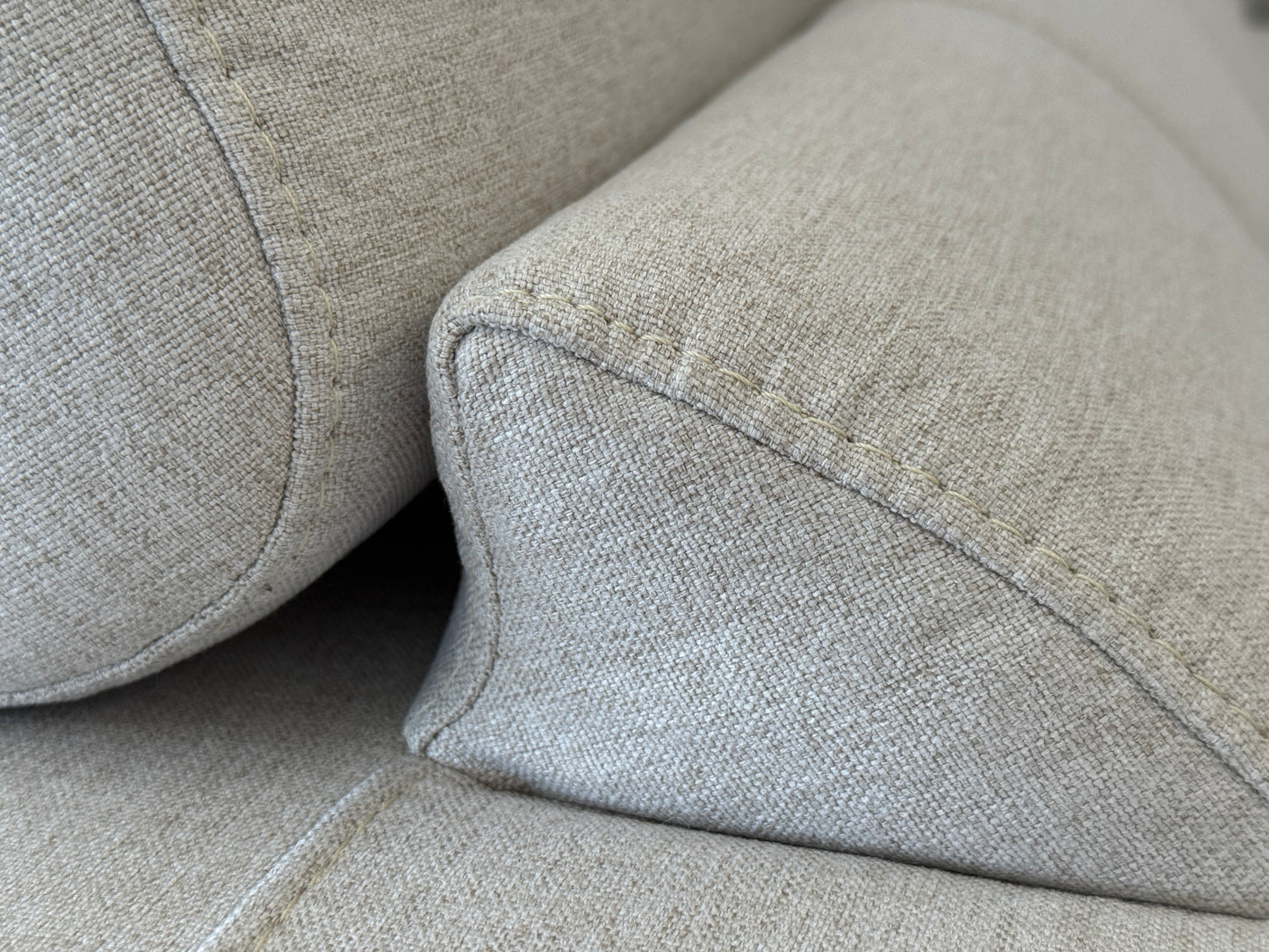 Close-up of a gray fabric sofa with a focus on texture and stitching.