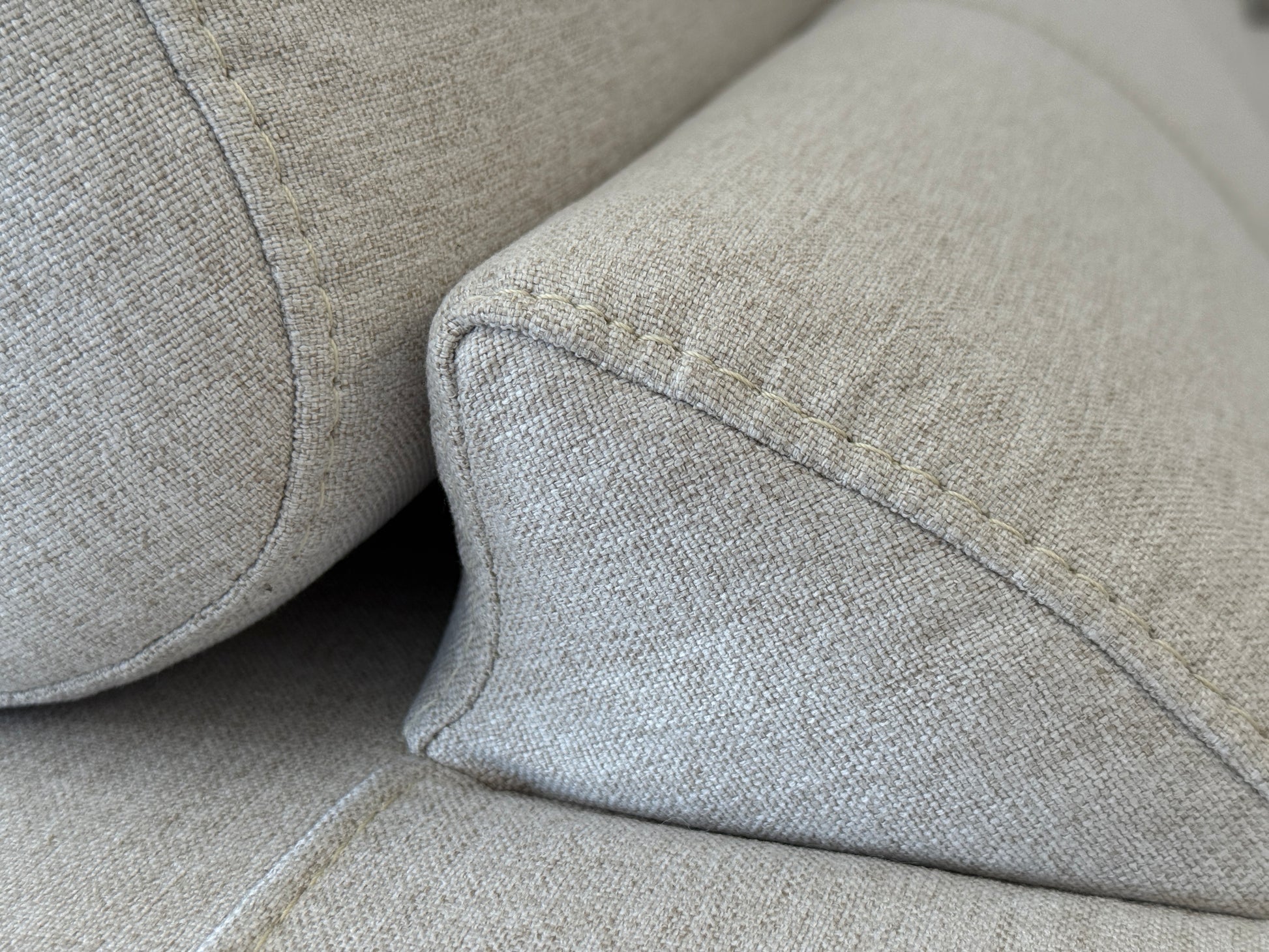 Close-up of a gray fabric sofa with a focus on texture and stitching.